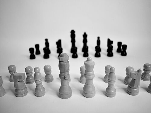 Schwarze und weiße Schachfiguren sind in gegenüberliegenden Reihen auf einer glatten Oberfläche angeordnet und schaffen ein Gefühl von Vorfreude und Strategie in einem minimalistischen Umfeld.
